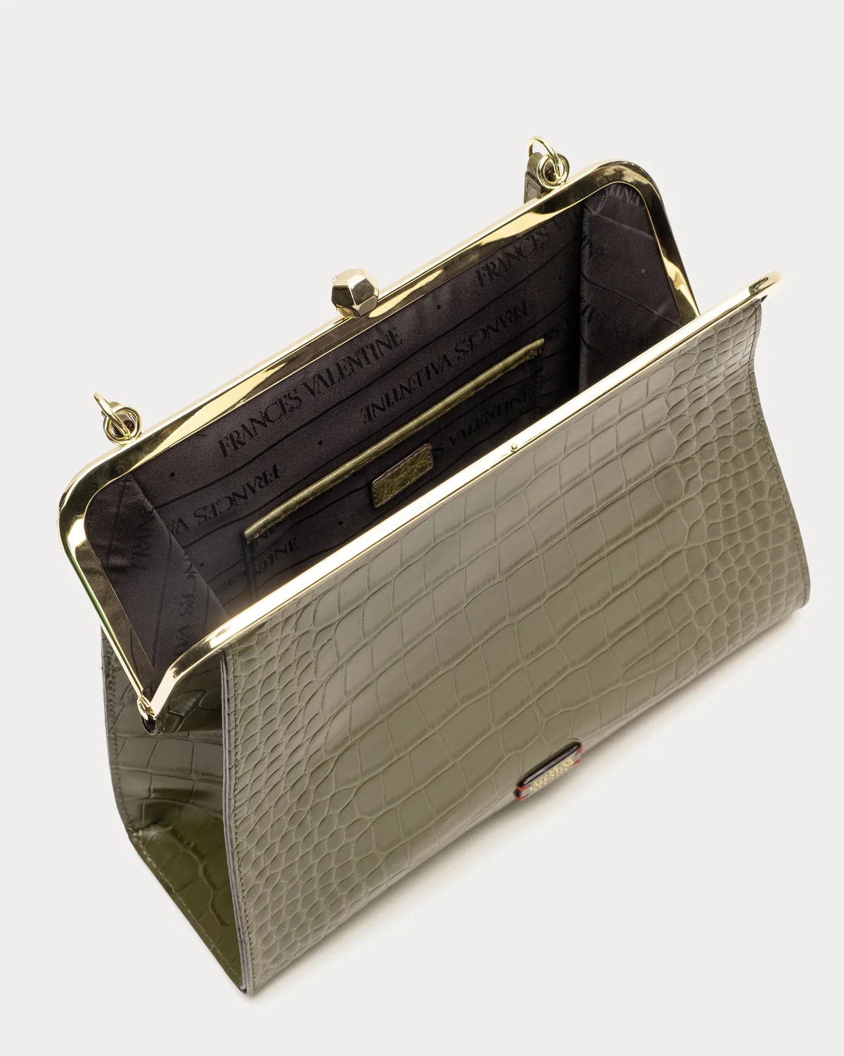 An open evening clutch bag with a glossy crocodile-embossed exterior in a muted olive green, featuring a gold-tone kiss-lock frame and a dark purple patterned interior.