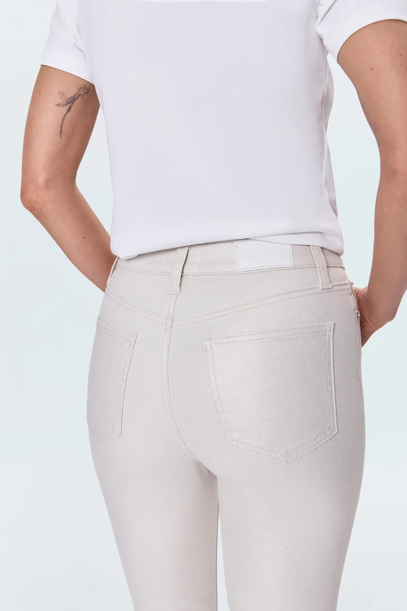 Rear view of a person wearing light beige high-waisted skinny jeans with a white t-shirt, showing the back pockets and waistband details.