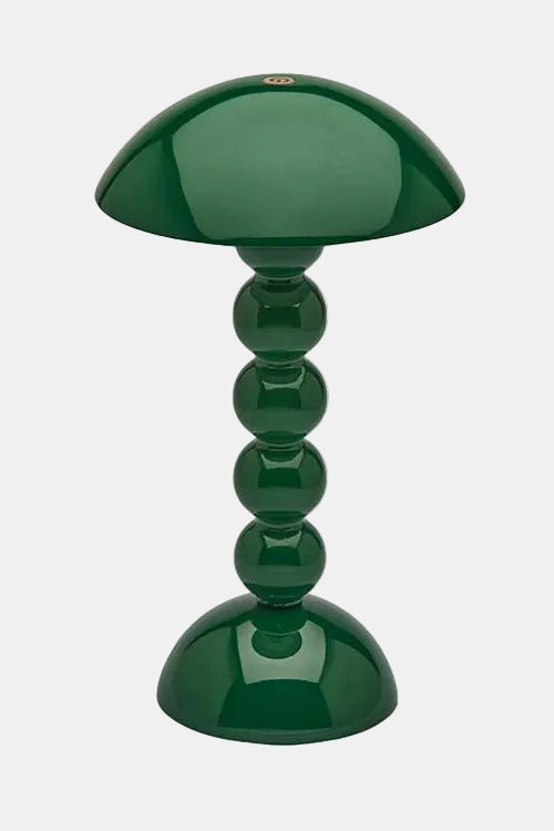 Green table lamp with a cylindrical base and rounded shade on a white background