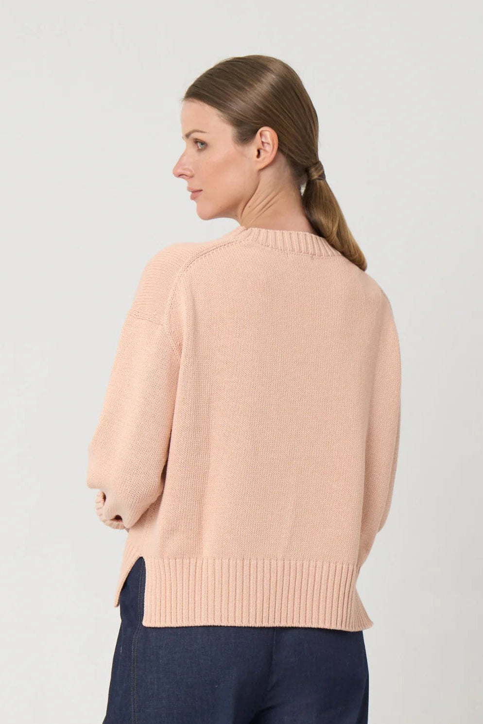 Woman wearing a light pink sweater on a plain background