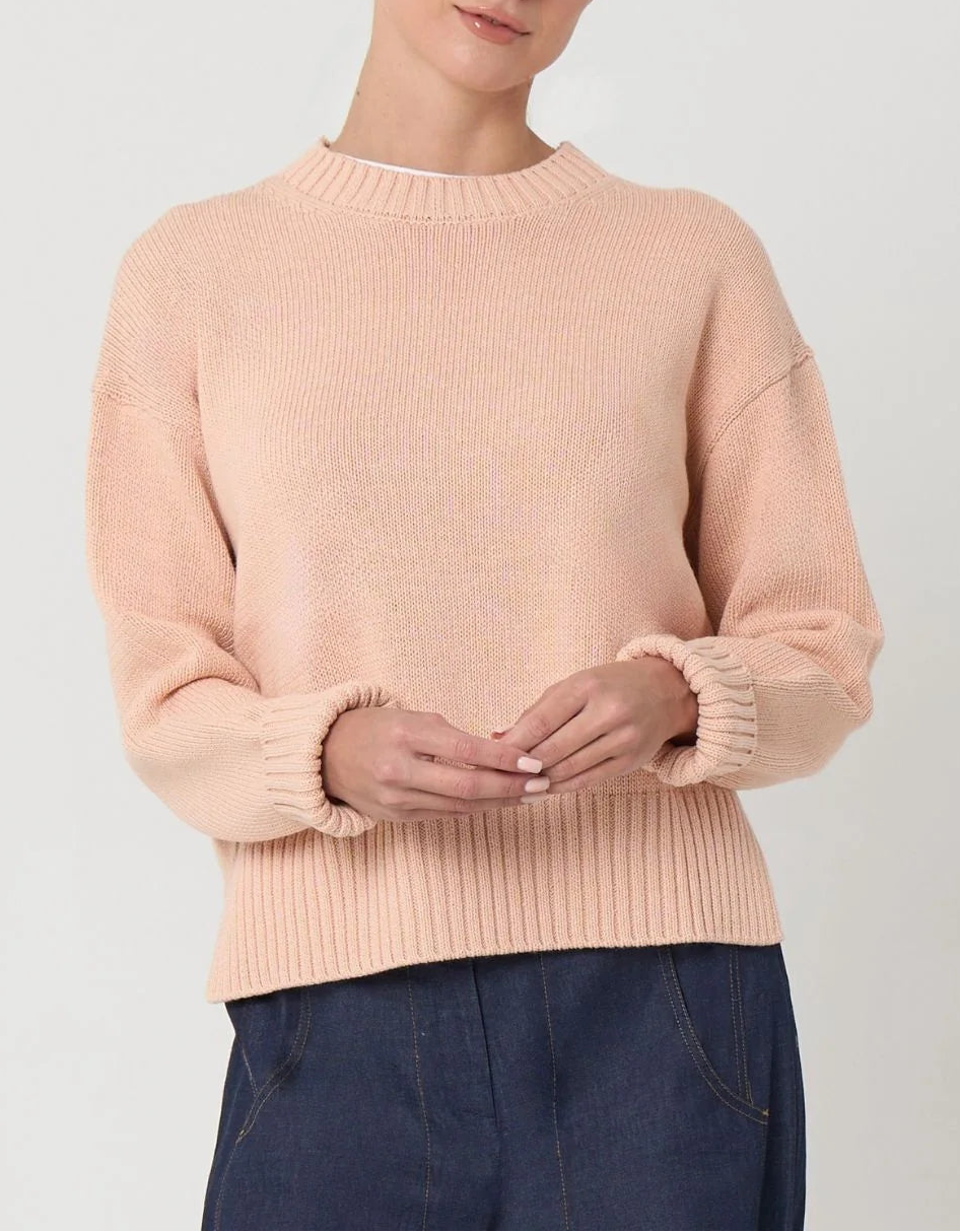 Woman wearing a light pink sweater against a plain background