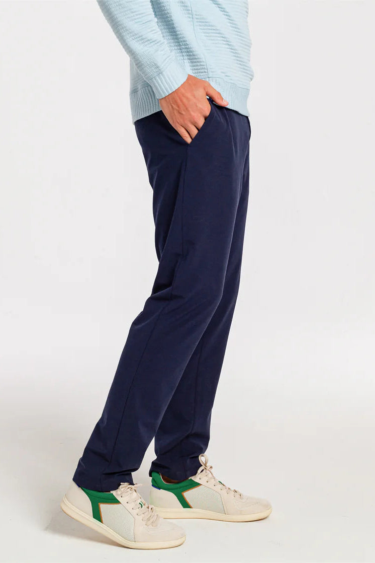 Person wearing navy blue pants and white sneakers on a white background