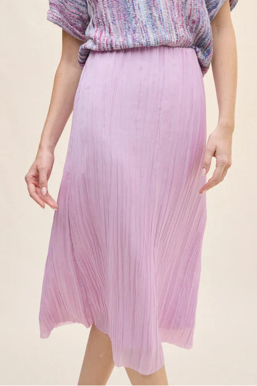 Woman wearing a colorful top and pink skirt on a beige background