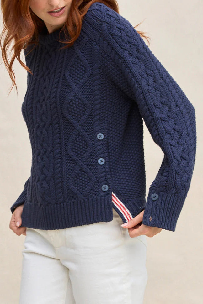 Woman wearing a navy blue cable knit sweater on a beige background