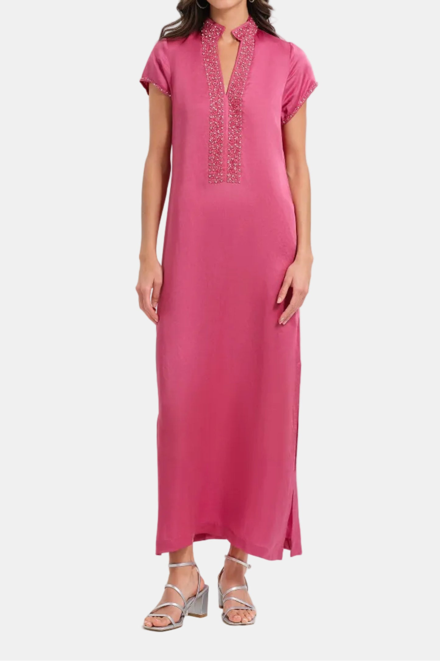 Woman wearing a pink dress with intricate detailing on a white background