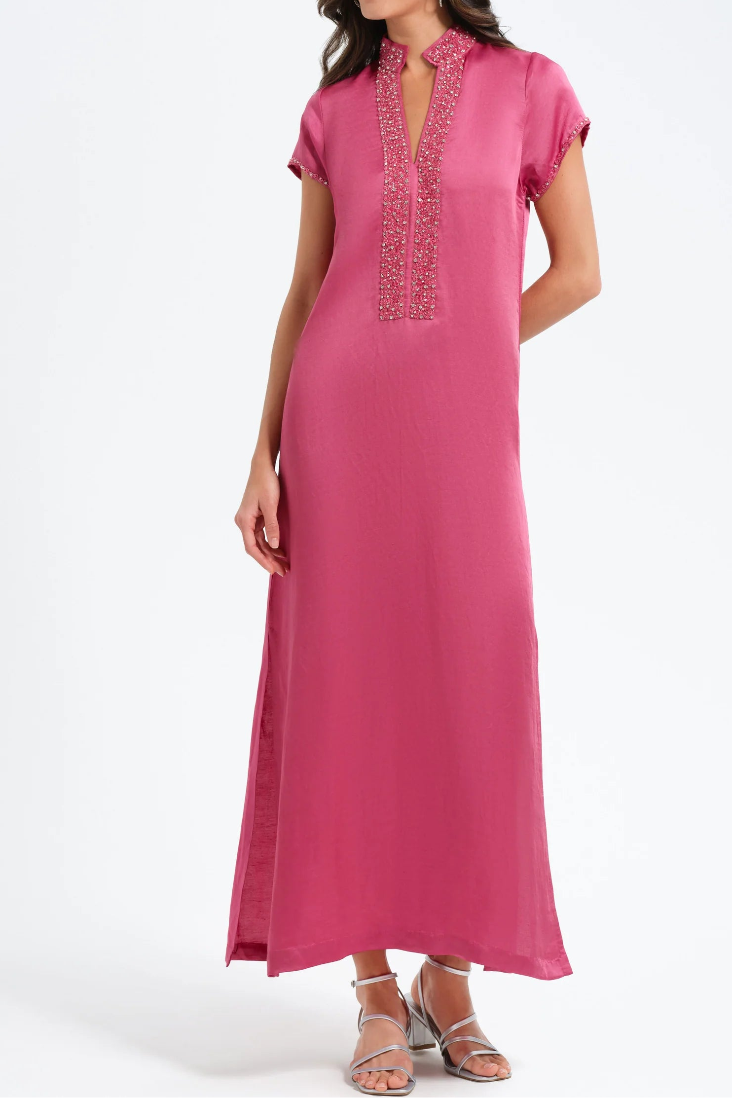 Woman wearing a pink dress with intricate detailing on a white background