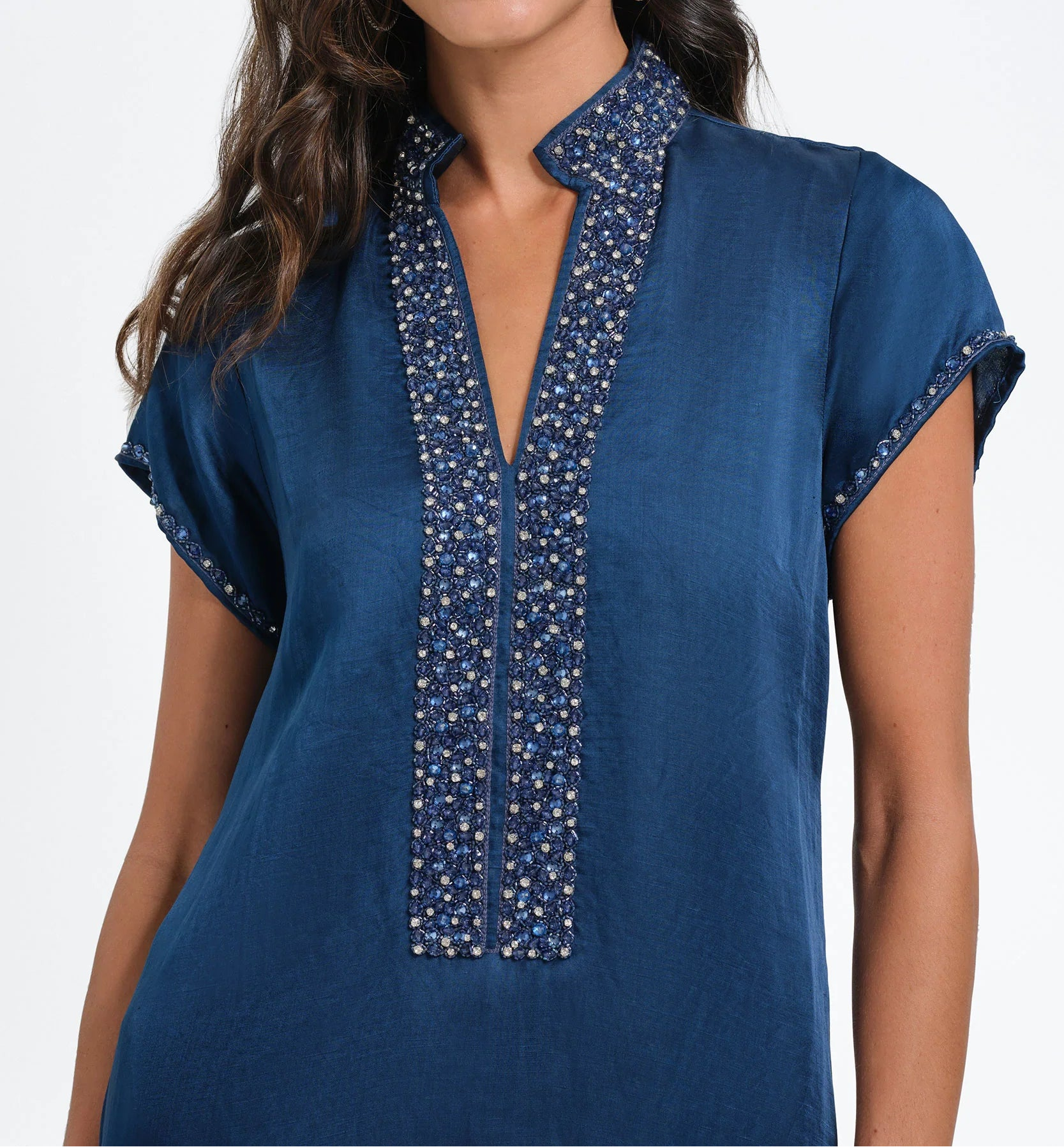 Woman wearing a blue blouse with intricate detailing on a white background
