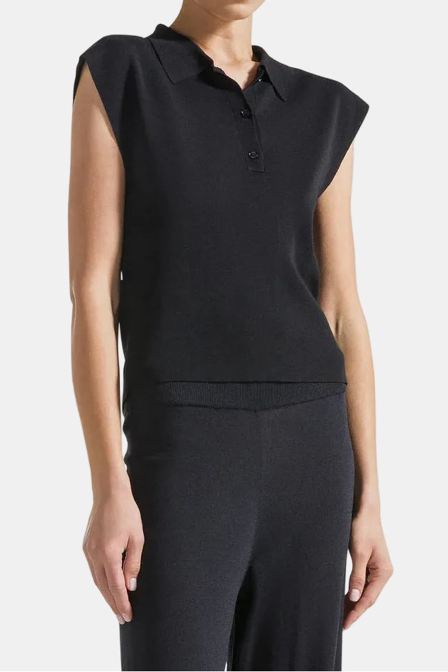 Woman wearing a black sleeveless polo shirt on a light background