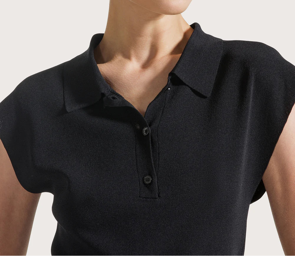 Woman wearing a black polo shirt against a plain background