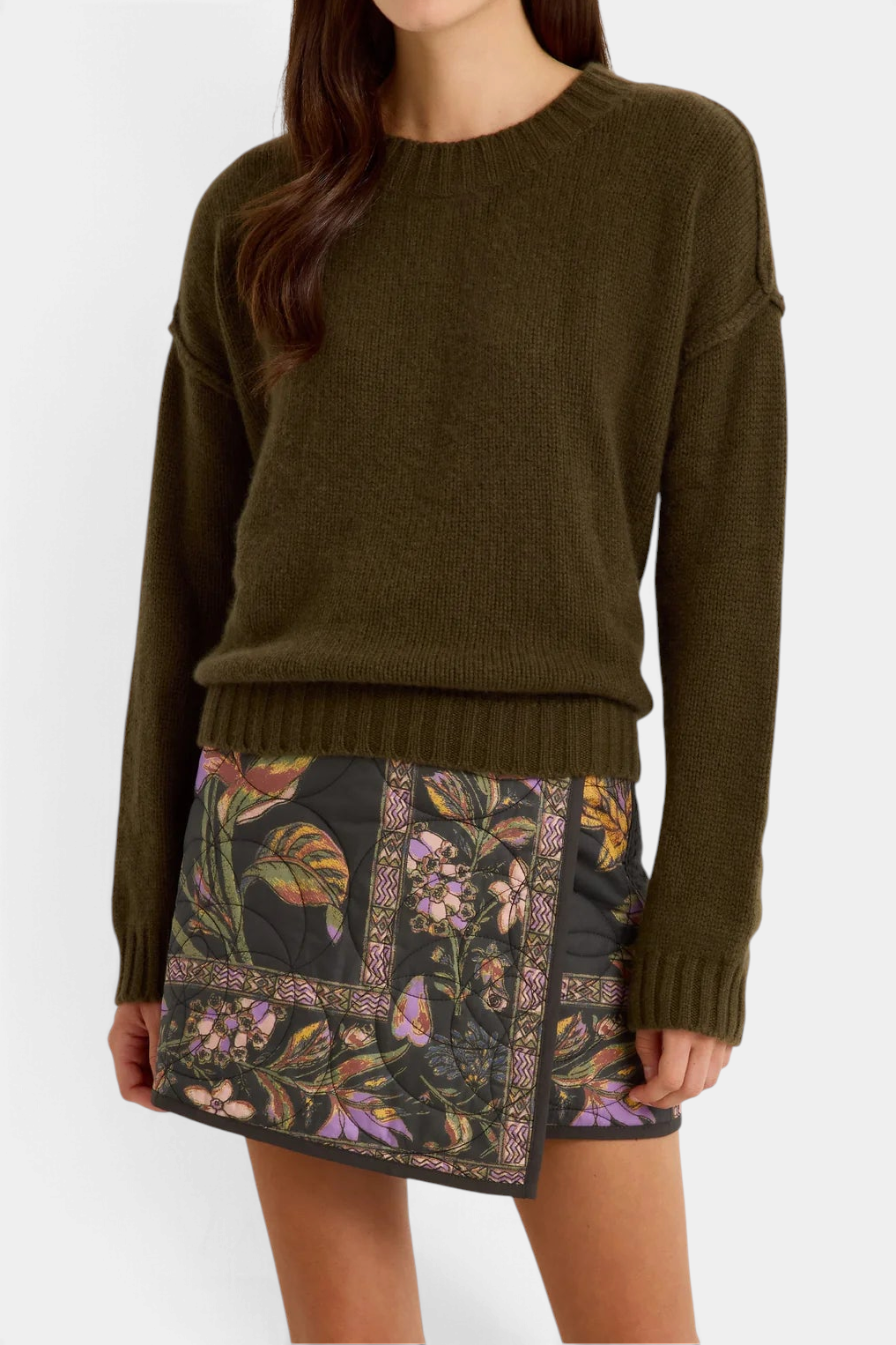 Marie Oliver  Ozzie sweater in olive green cashmere with a ribbed crew neck, worn with a floral quilted mini skirt.