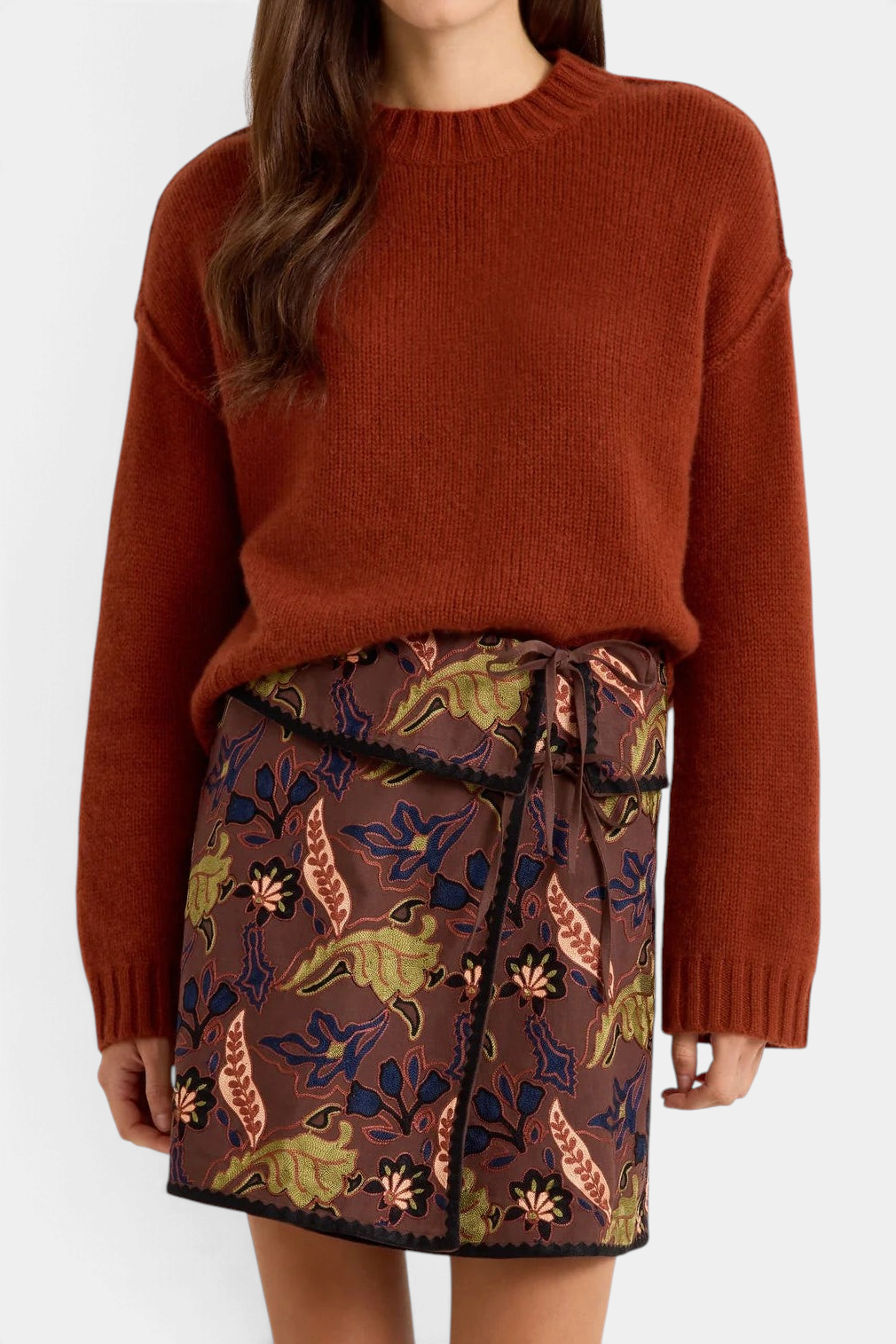 Marie Oliver Ozzie sweater in rust brown cashmere with a crew neck, worn with a patterned wrap skirt.