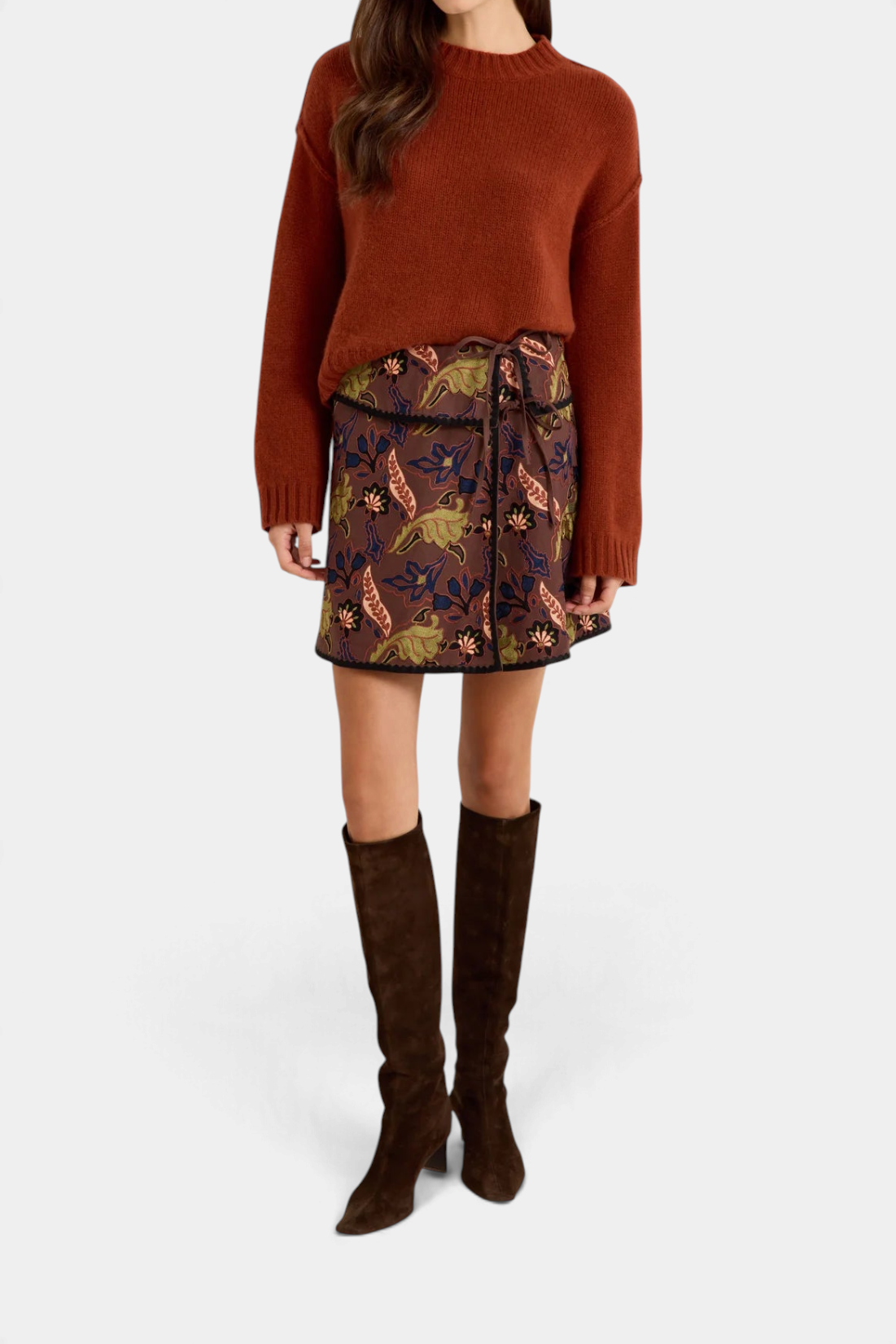 Marie Oliver  Ozzie sweater in rust cashmere worn with a floral print mini skirt and brown suede knee-high boots