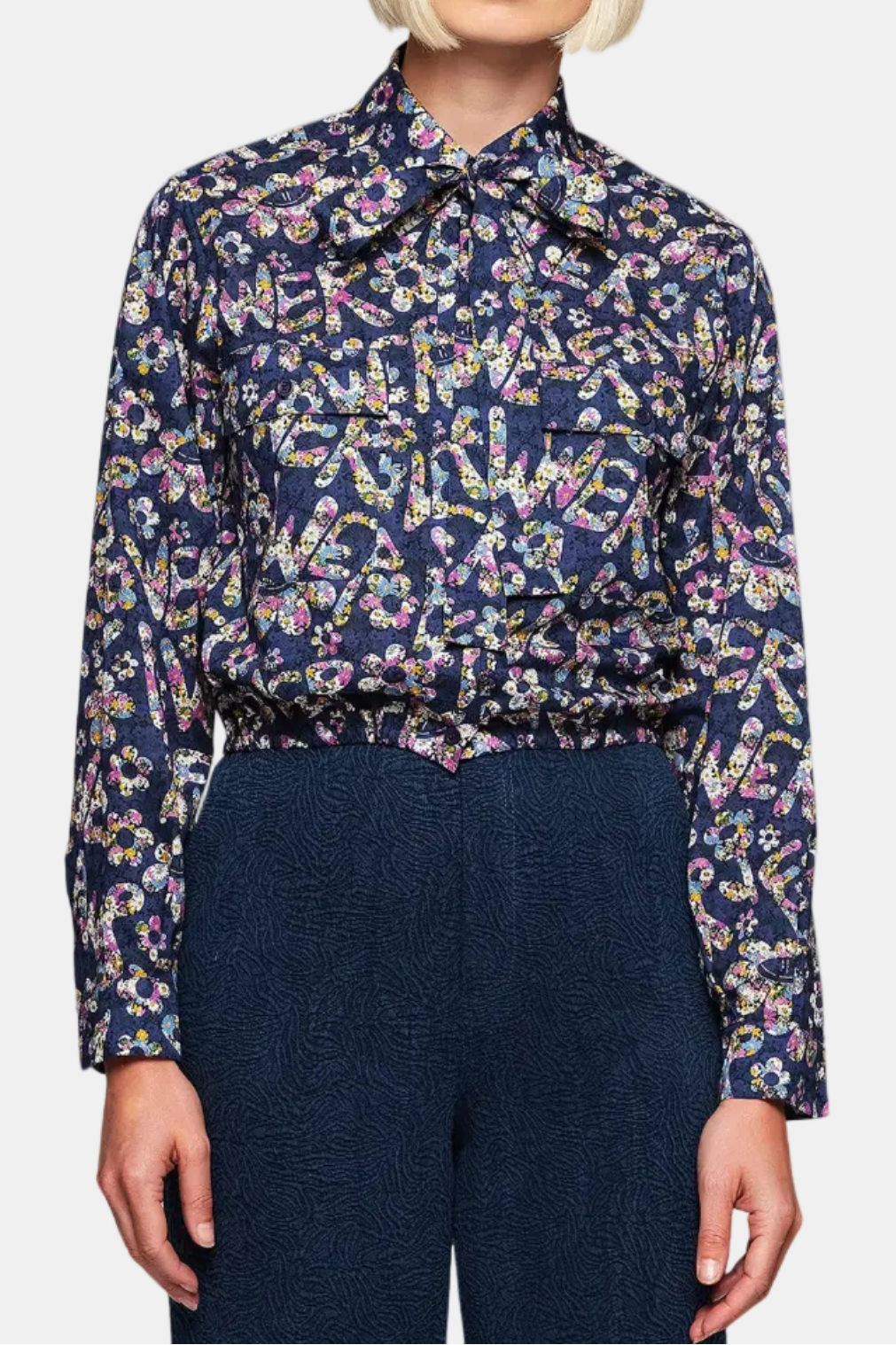 A woman wearing a floral print blue cotton shirt with long sleeves and a removable collar tie.