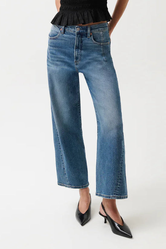 Woman wearing a black sleeveless top and blue jeans on a white background