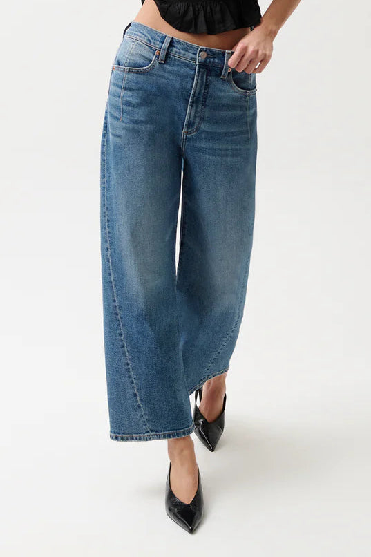 Woman wearing a black sleeveless top and blue jeans on a white background