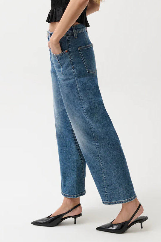 Woman wearing a black top and blue jeans on a white background
