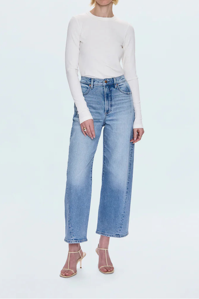 Person wearing a white long-sleeve top and light blue jeans on a white background