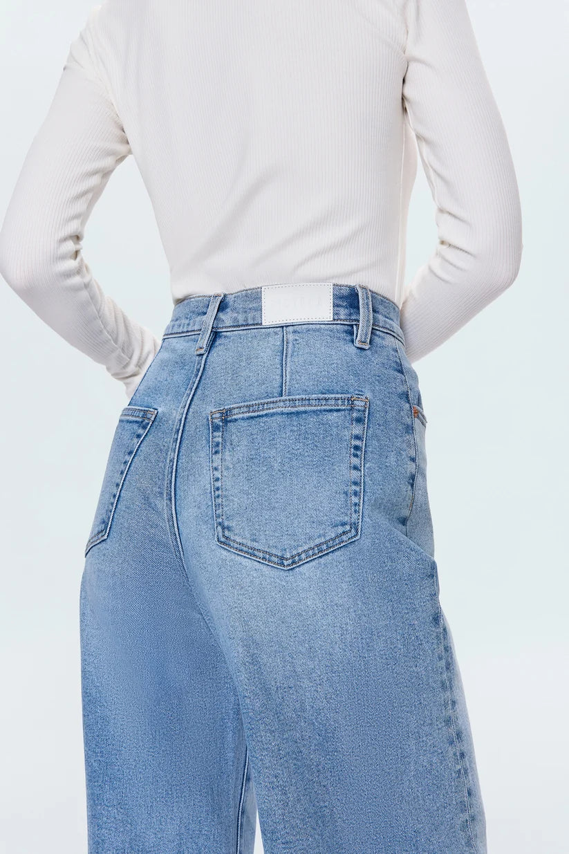 Person wearing light blue jeans and a white long-sleeve shirt on a light gray background