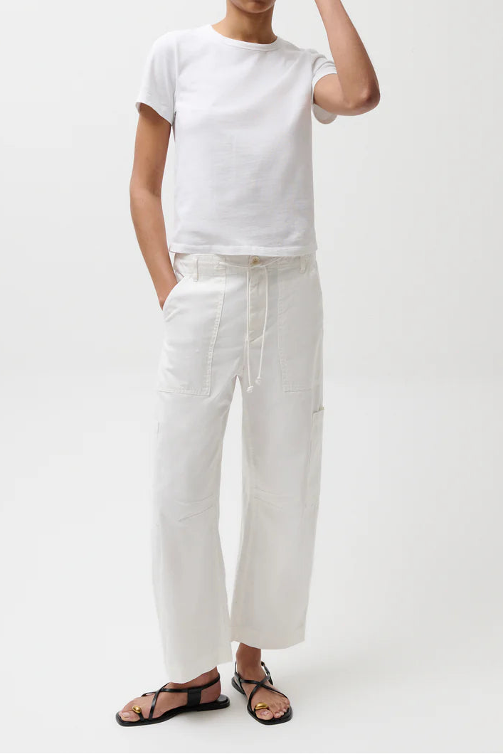 Person wearing a white t-shirt, white pants, and a green cap on a white background