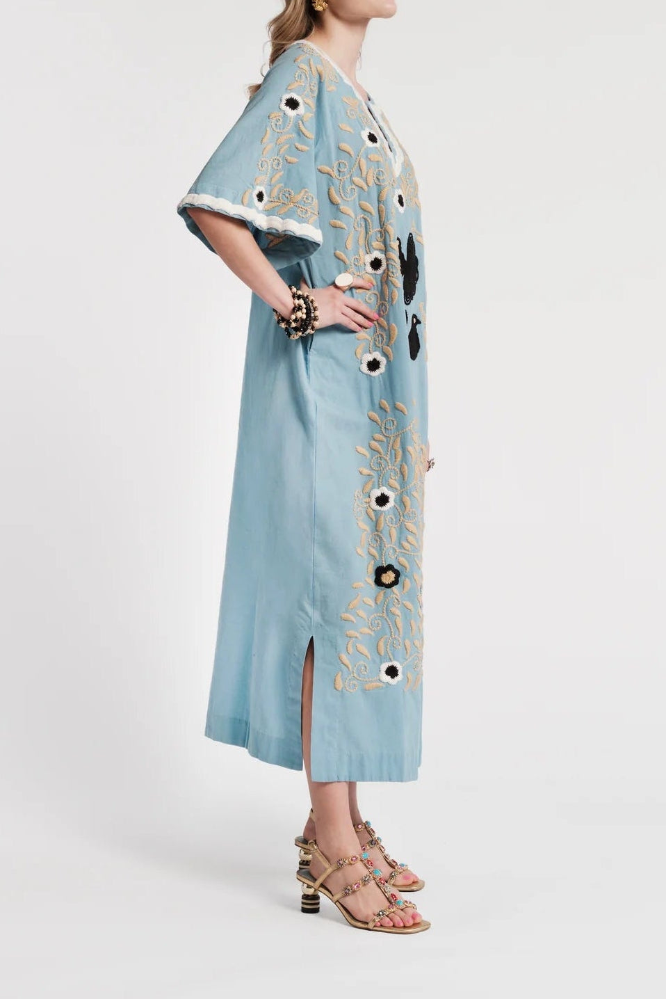 Woman wearing a light blue dress with decorative elements on a white background