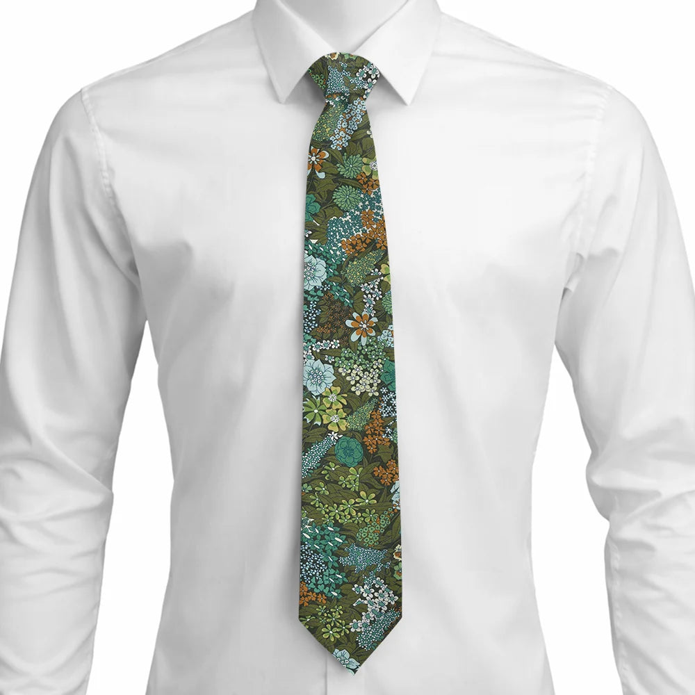 A men's necktie with a dense botanical and floral pattern in shades of green, teal, blue, and brown, styled on a white dress shirt.