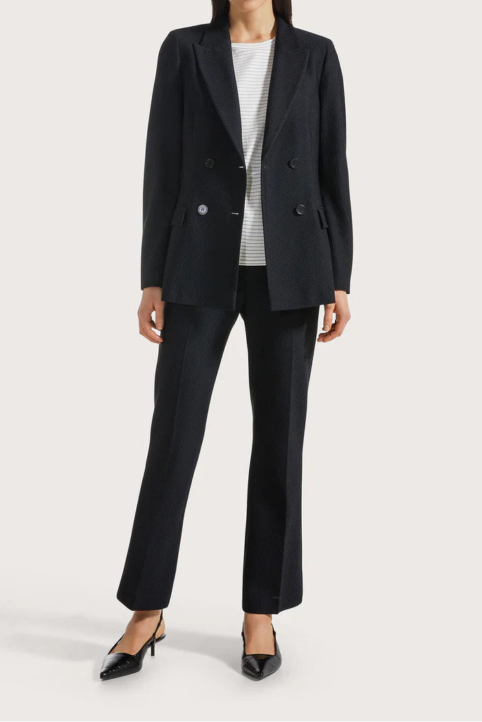Woman wearing a black suit with a white shirt on a light gray background