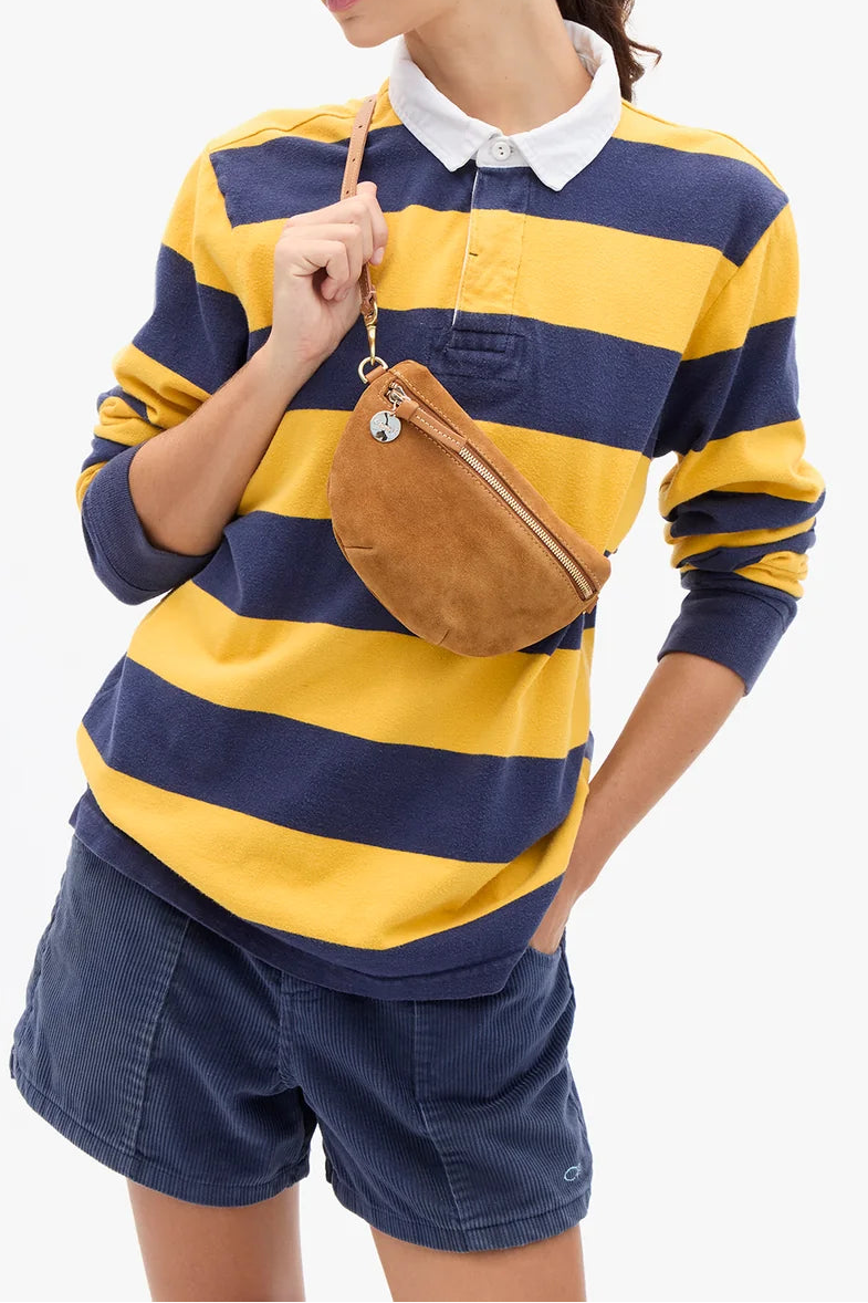 A woman modeling a yellow and navy blue horizontally striped long-sleeve polo shirt with a white collar, paired with navy shorts and a brown suede crossbody bag, against a plain white background.