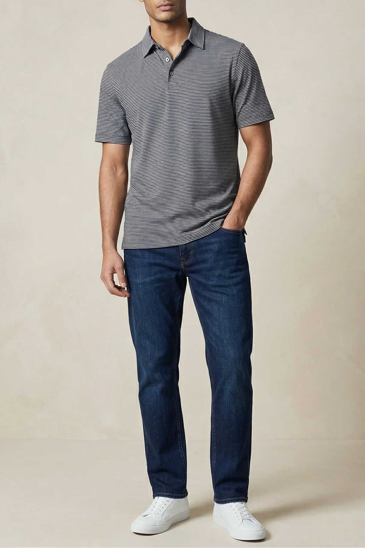 Man wearing a gray polo shirt and blue jeans against a beige background
