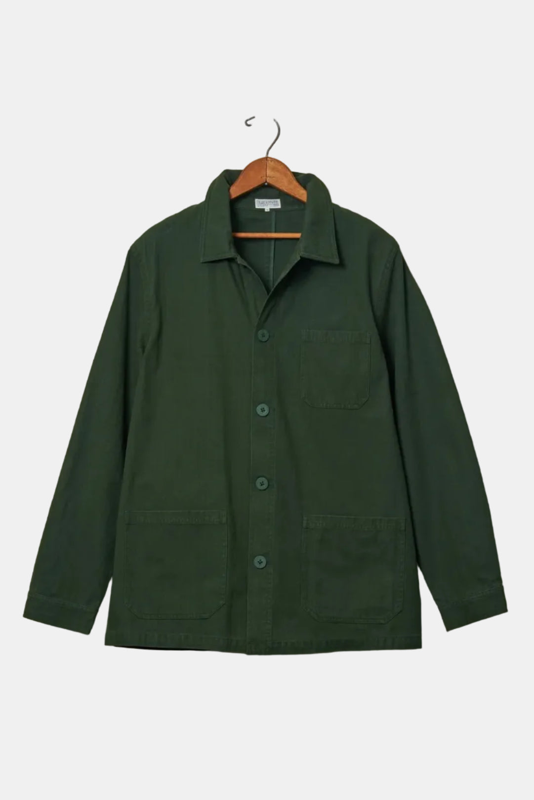 Green jacket hanging on a wooden hanger against a beige wall.