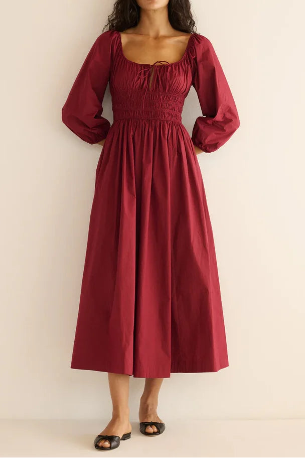 Woman wearing a burgundy dress against a beige background