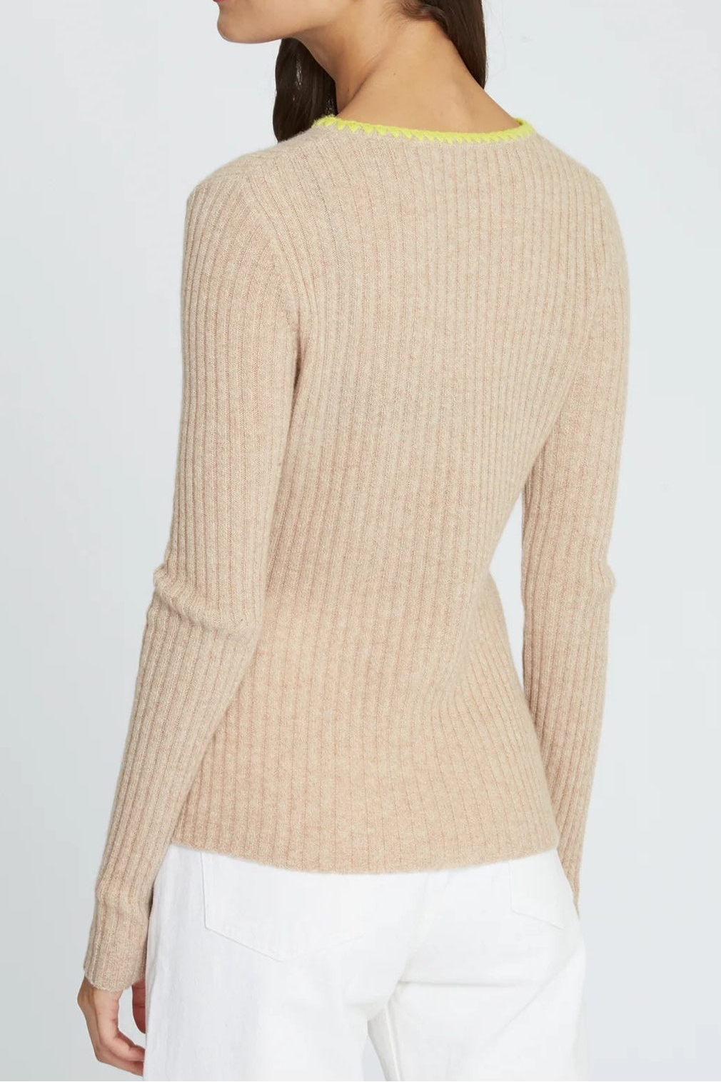 Woman wearing a beige ribbed sweater with a white background