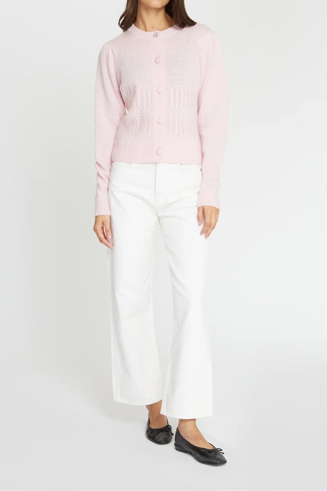 Woman wearing a light pink blouse and white pants on a white background