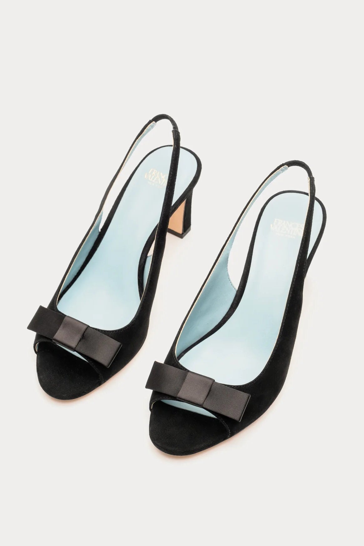 Black high-heeled shoes with bow details on a light gray background
