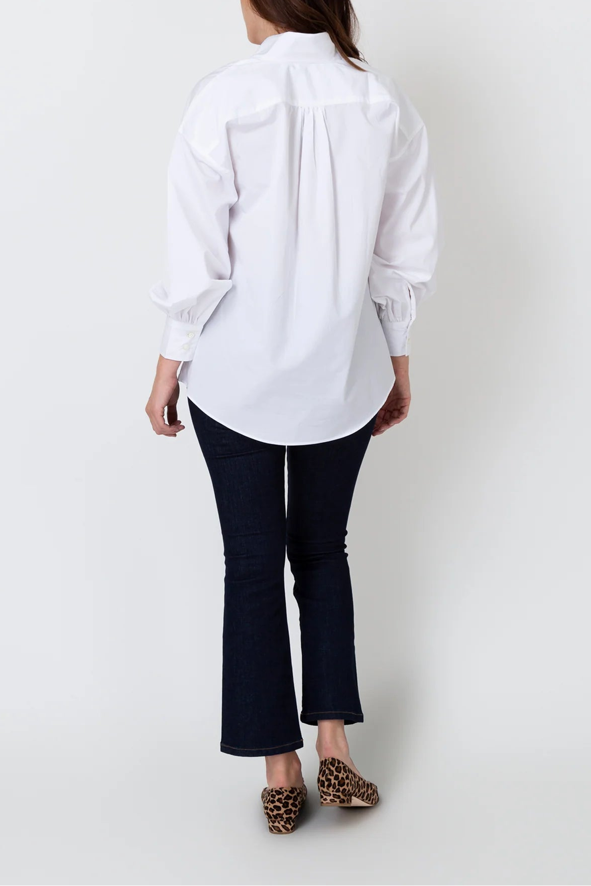 Person wearing a white shirt and dark pants against a white background