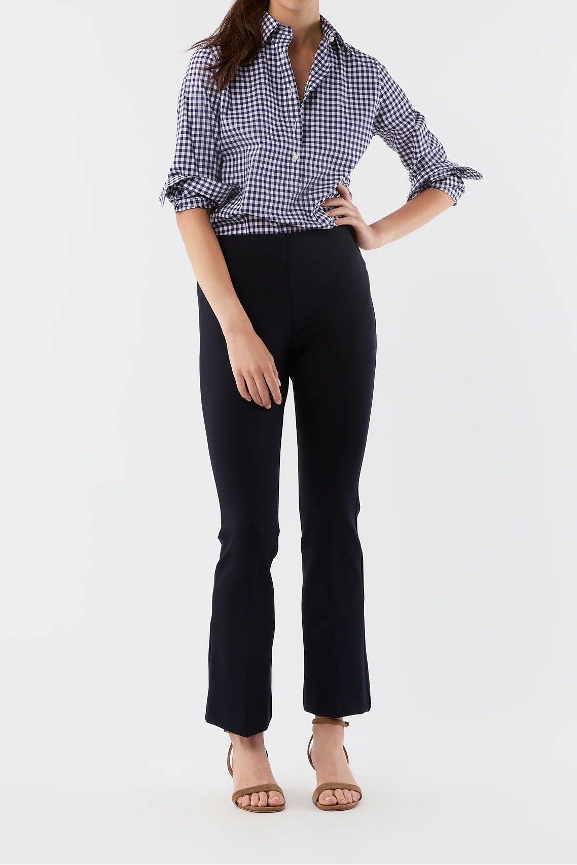 Woman wearing a checkered shirt and black pants on a white background