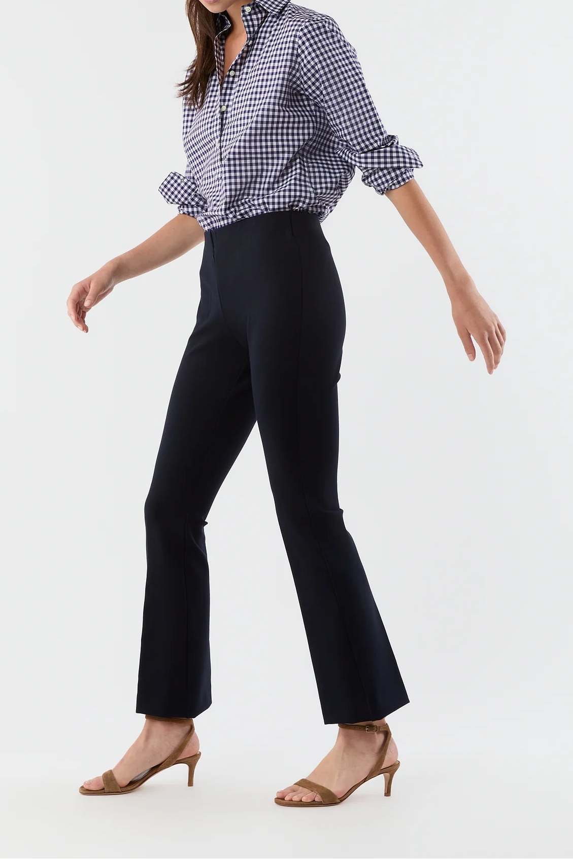Woman wearing a checkered shirt and black pants on a white background