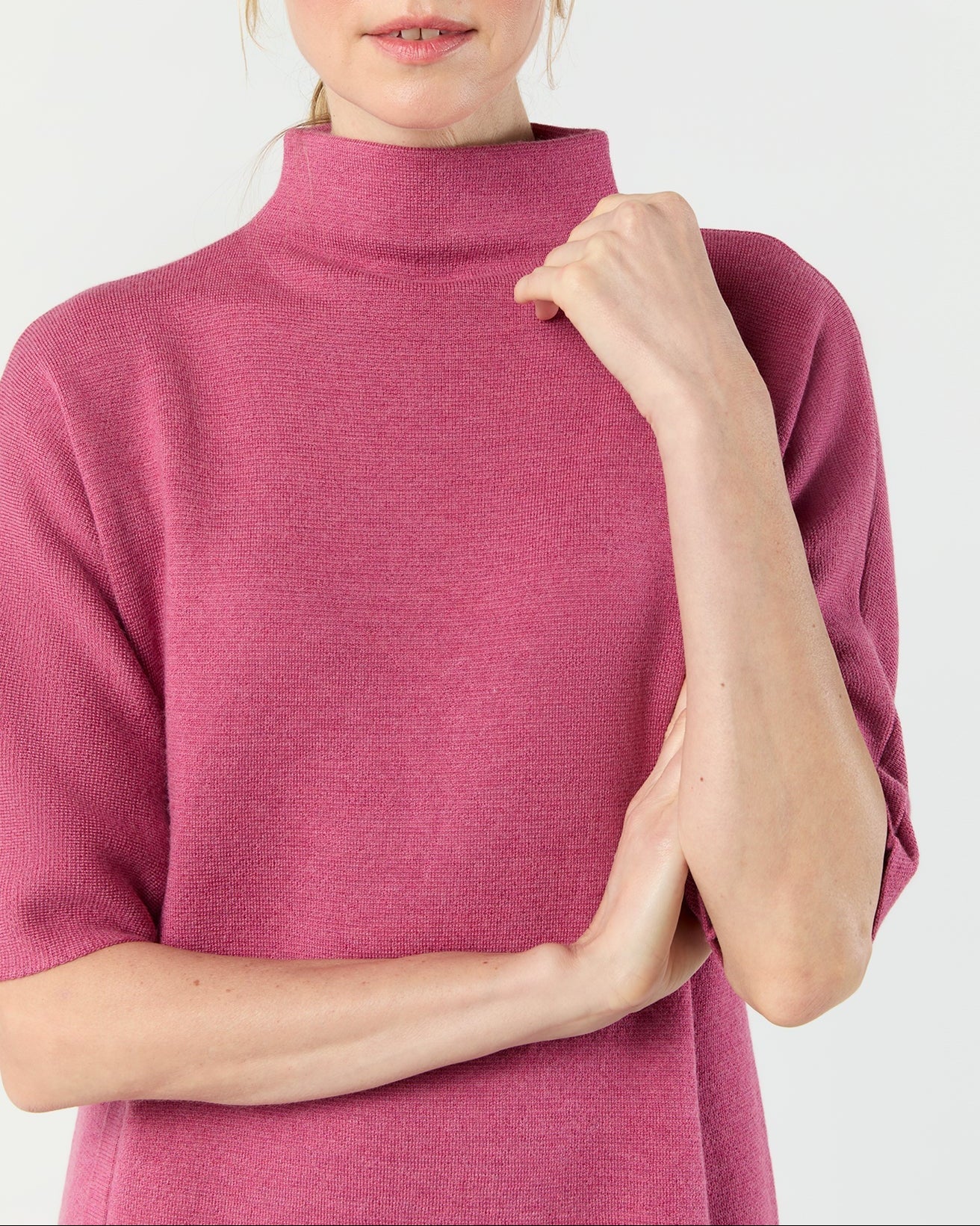 Woman wearing a pink turtleneck sweater on a white background