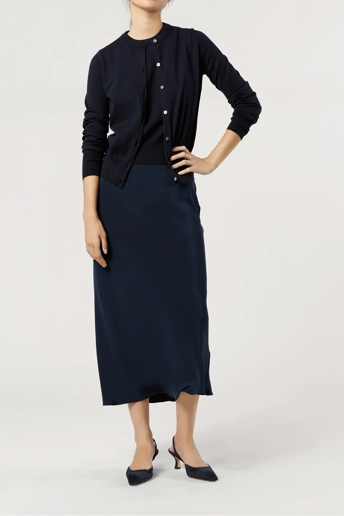 Woman wearing a navy blue cardigan and skirt on a white background