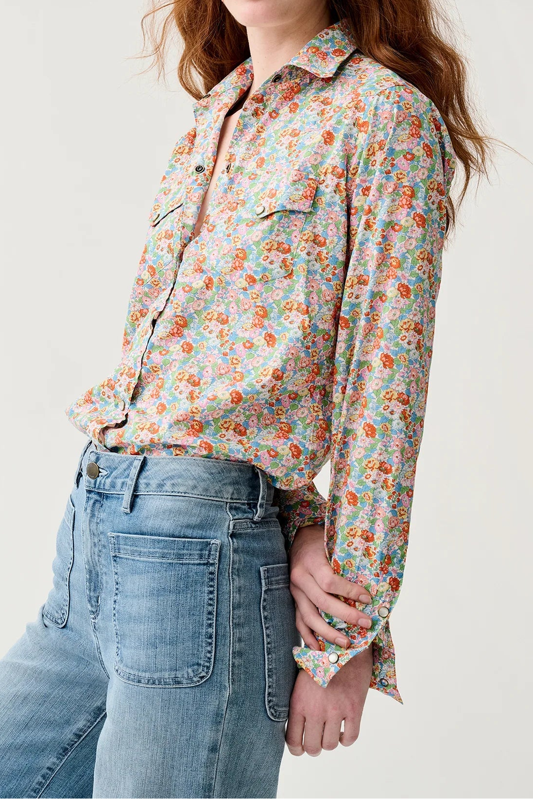 Woman wearing a floral shirt and jeans on a plain background