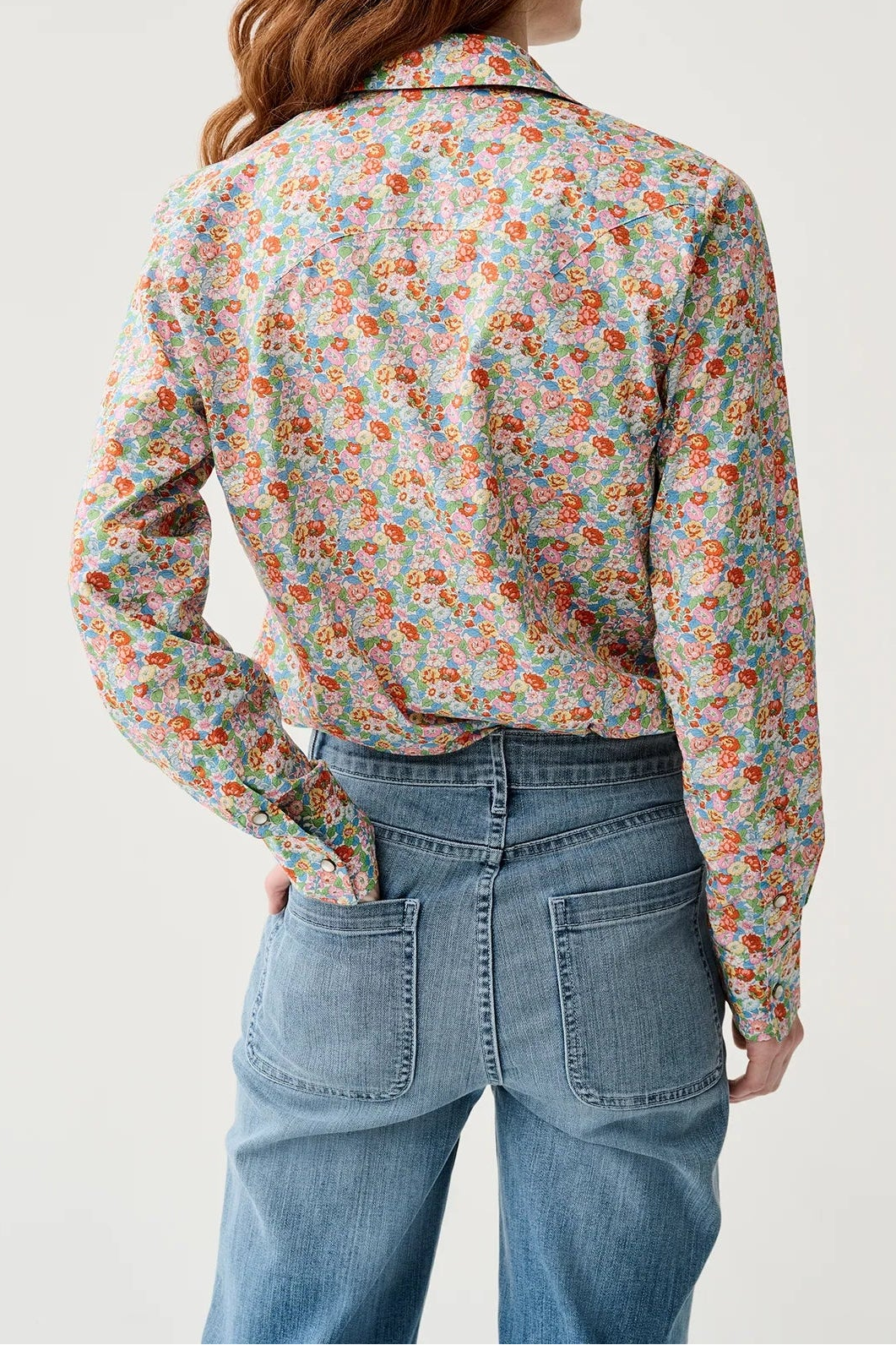 Person wearing a floral shirt and blue jeans on a white background