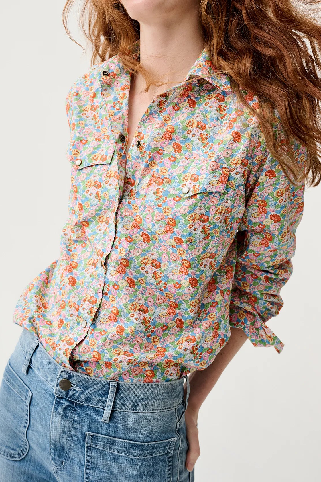 Woman wearing a floral shirt and jeans on a white background