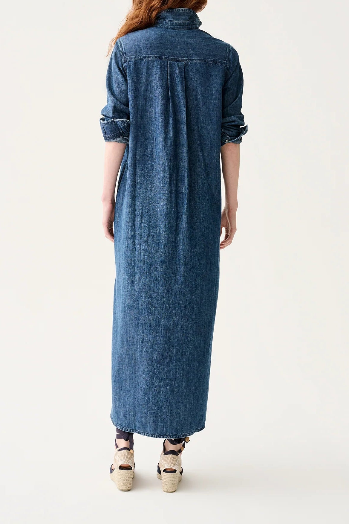 Woman wearing a long blue denim dress on a white background