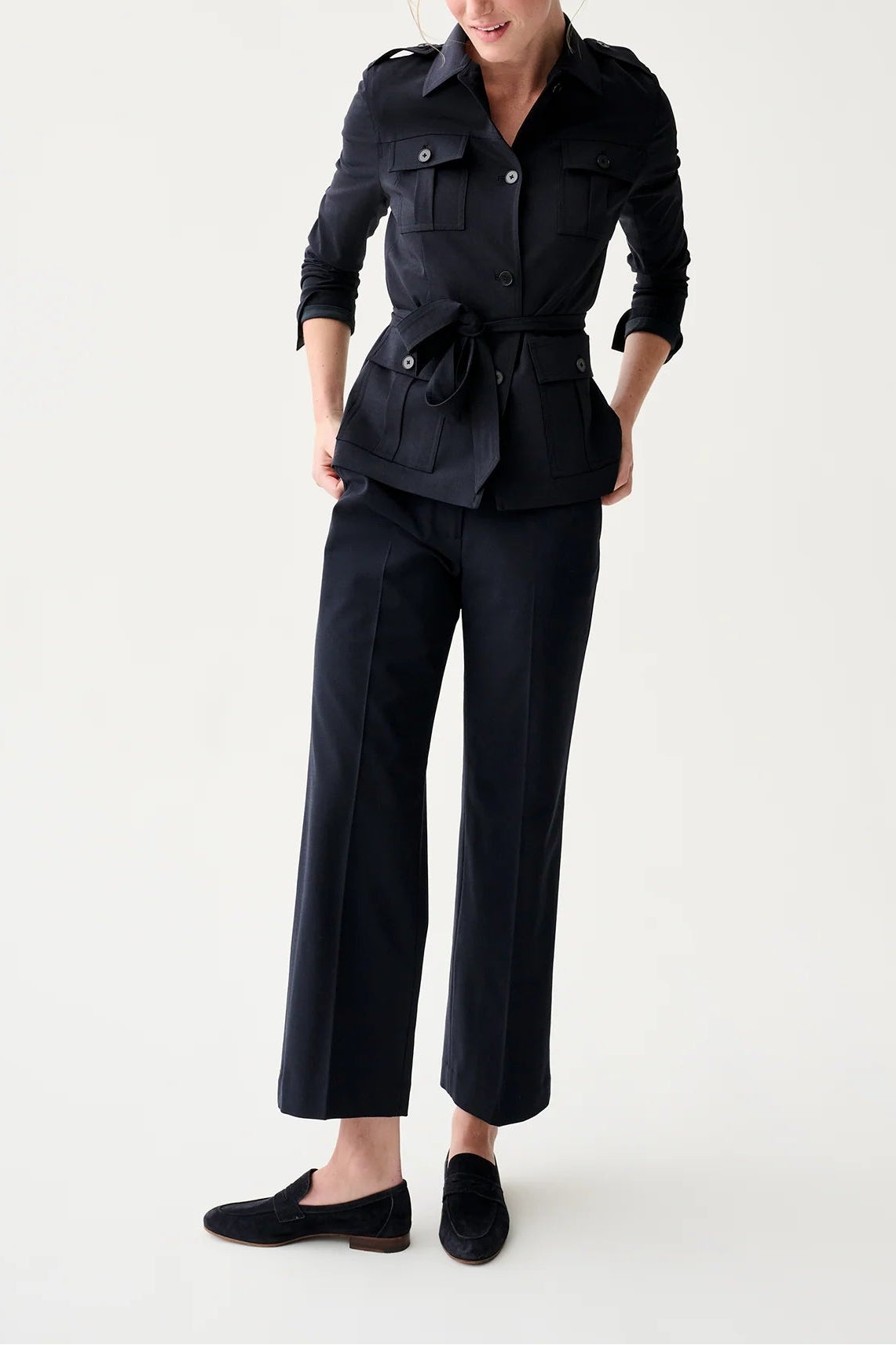 Woman wearing a black outfit with a jacket and pants on a white background