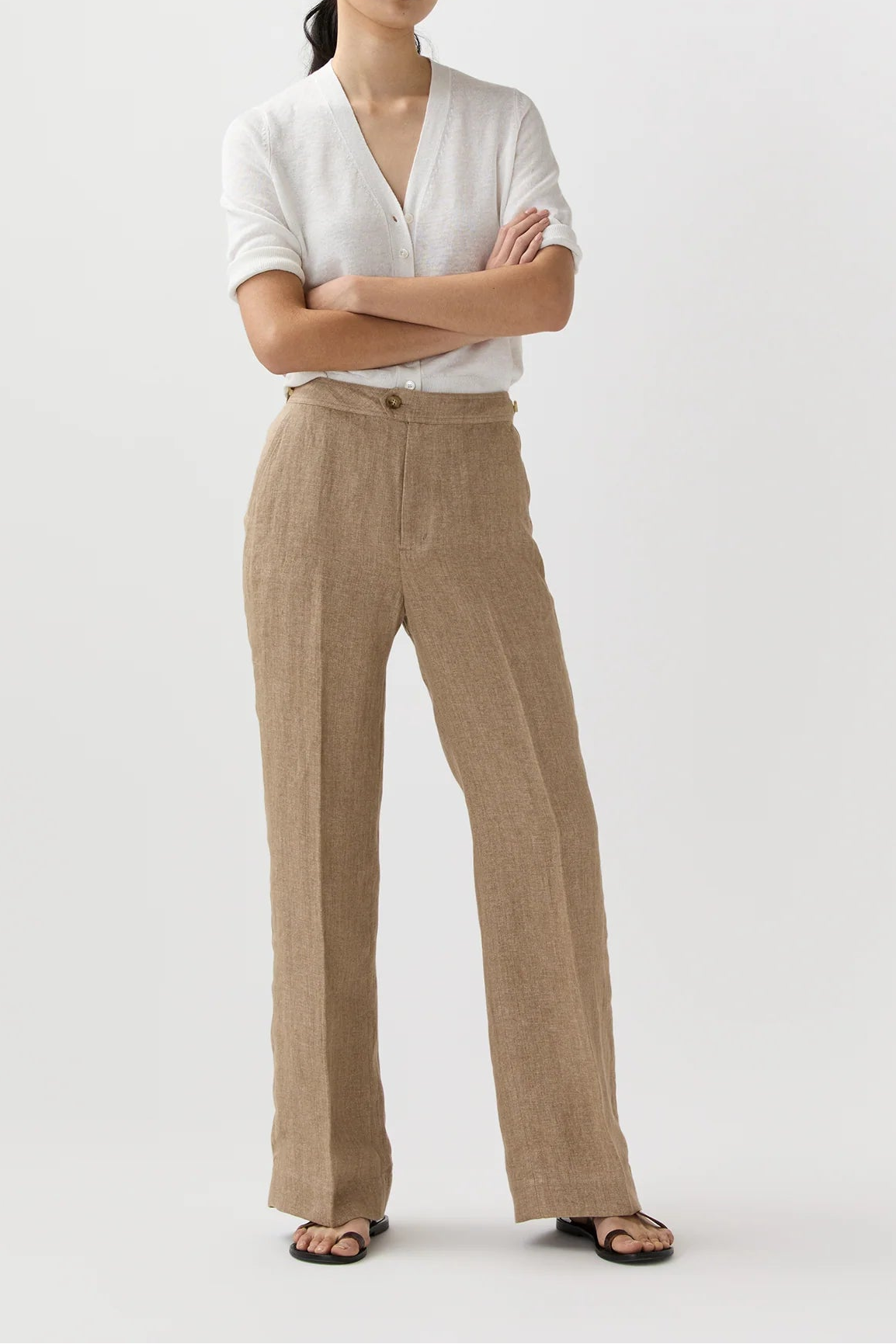 Woman wearing a white shirt and beige pants on a white background
