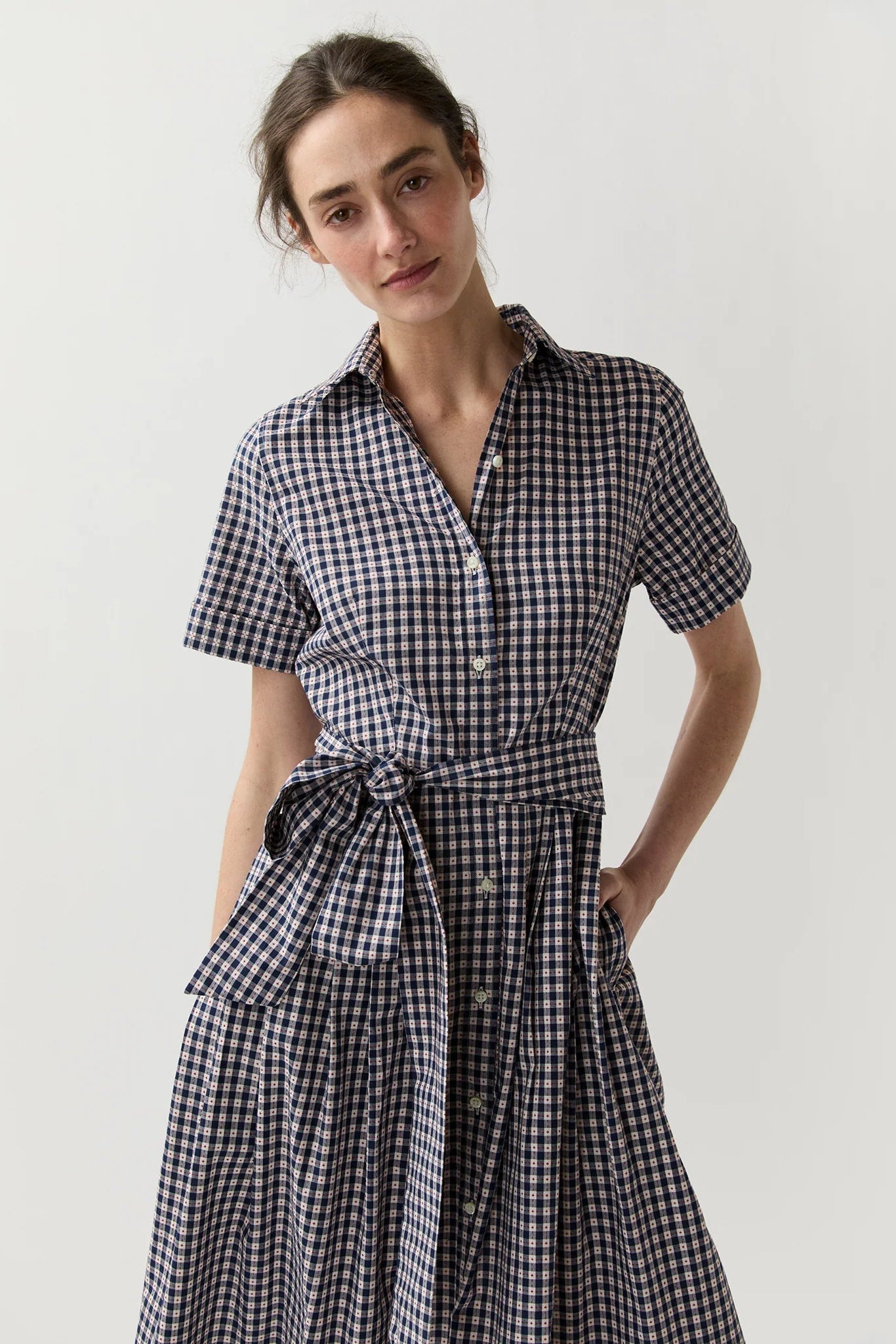 Woman wearing a black and white checkered dress on a plain background