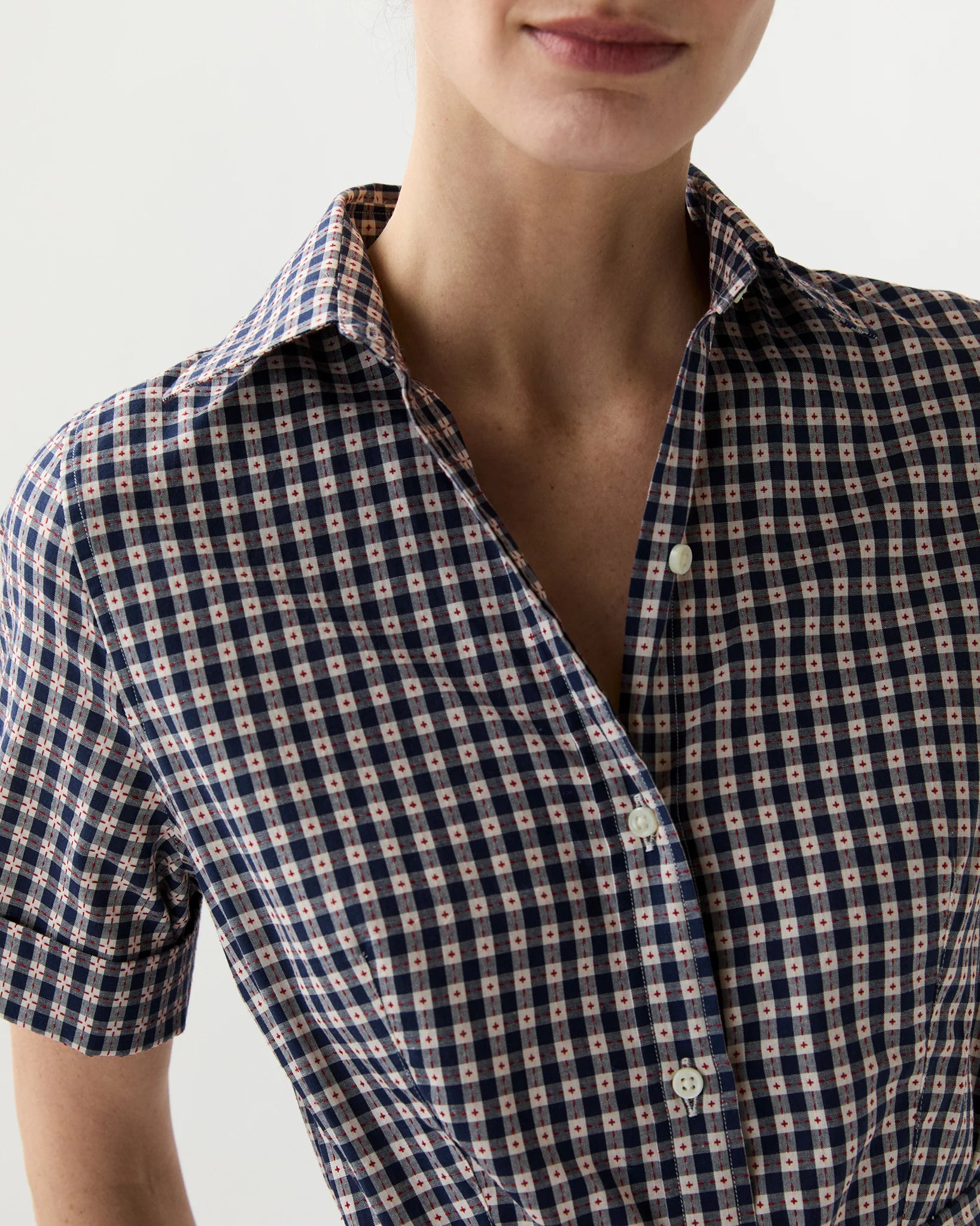 Close-up of a person wearing a checkered shirt with a neutral background