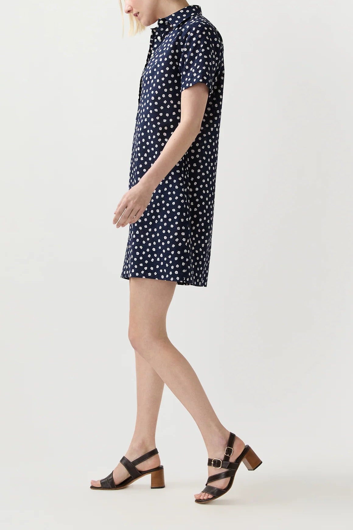 Woman wearing a navy dress with white polka dots on a light gray background