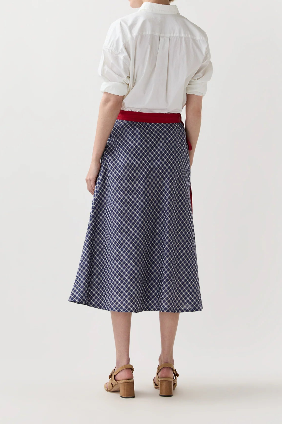 Woman wearing a white blouse and patterned skirt on a plain background