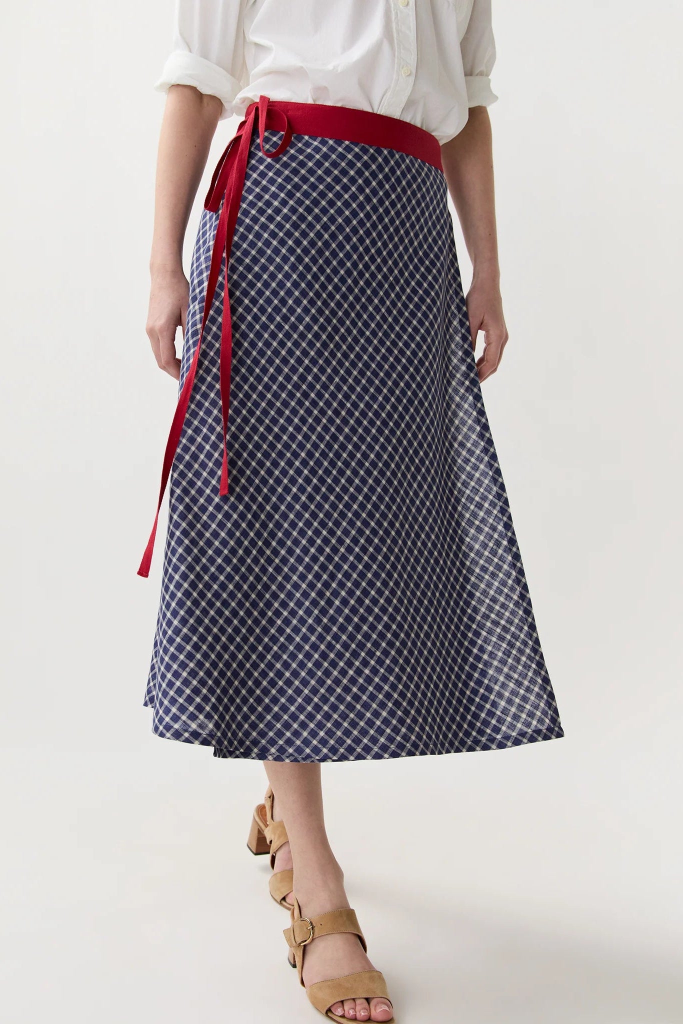 Person wearing a navy checkered skirt with a red belt on a white background
