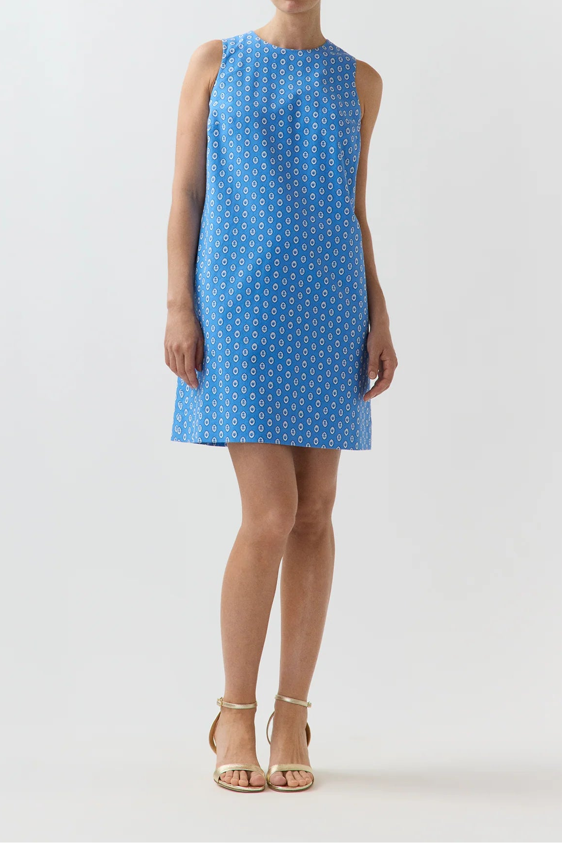 Woman wearing a blue dress with white geometric pattern on a white background